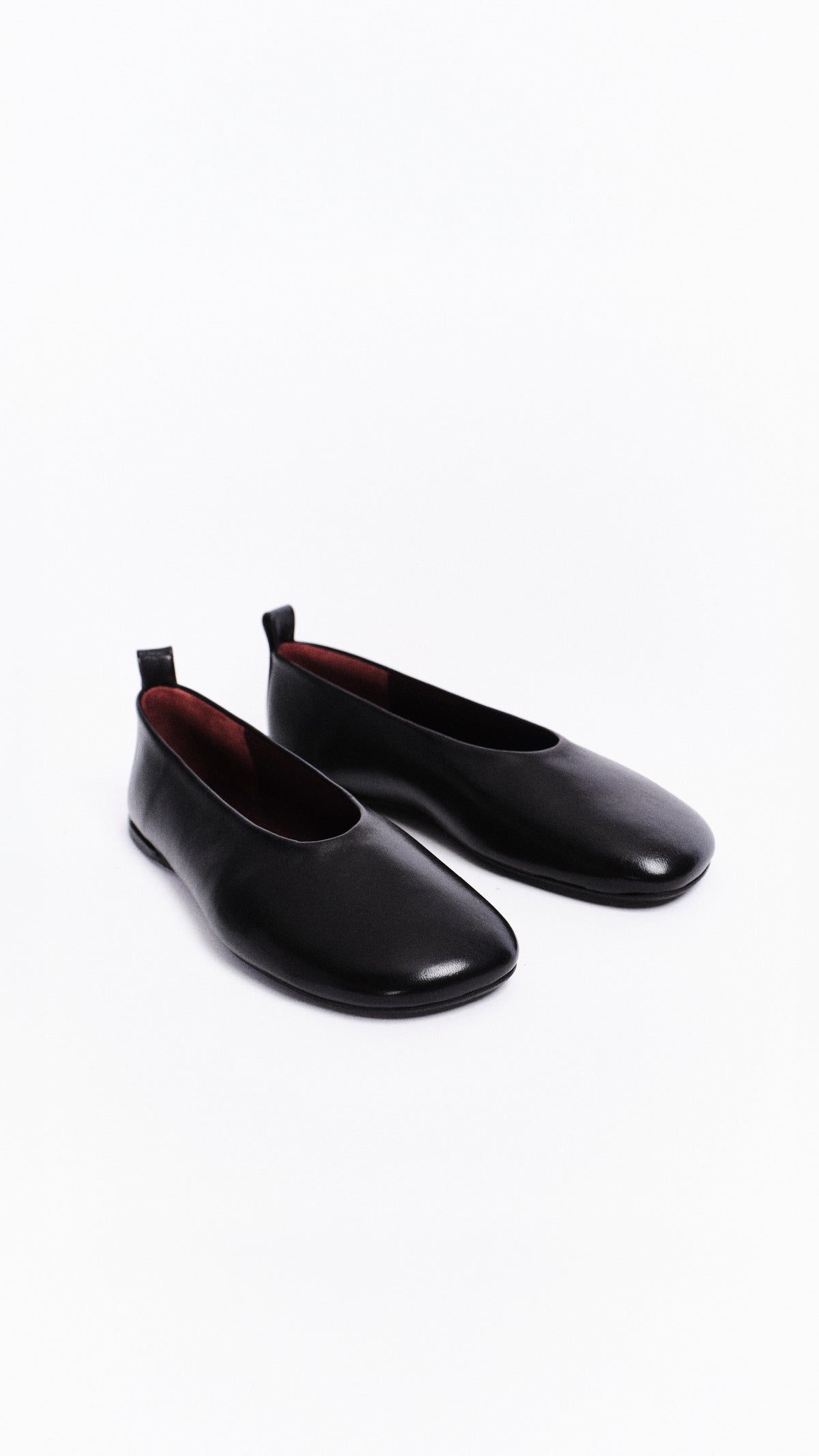 Pair of black leather barefoot flats on a white background