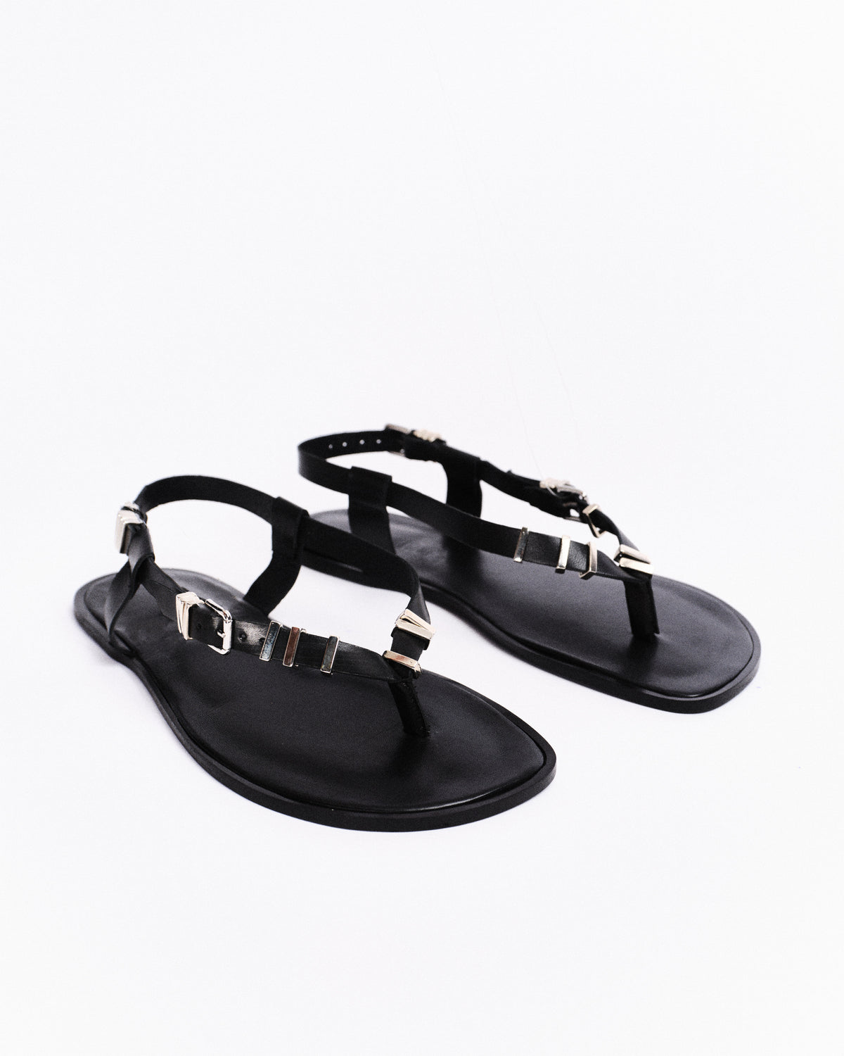 Black barefoot sandals with metallic straps on a white background