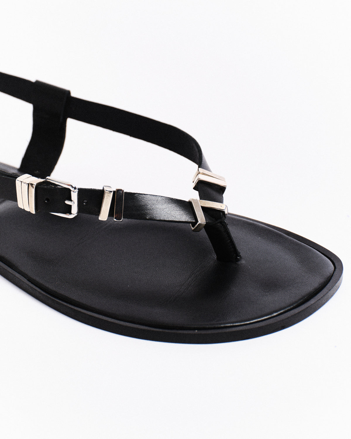 Black barefoot sandal with metallic buckles on a white background