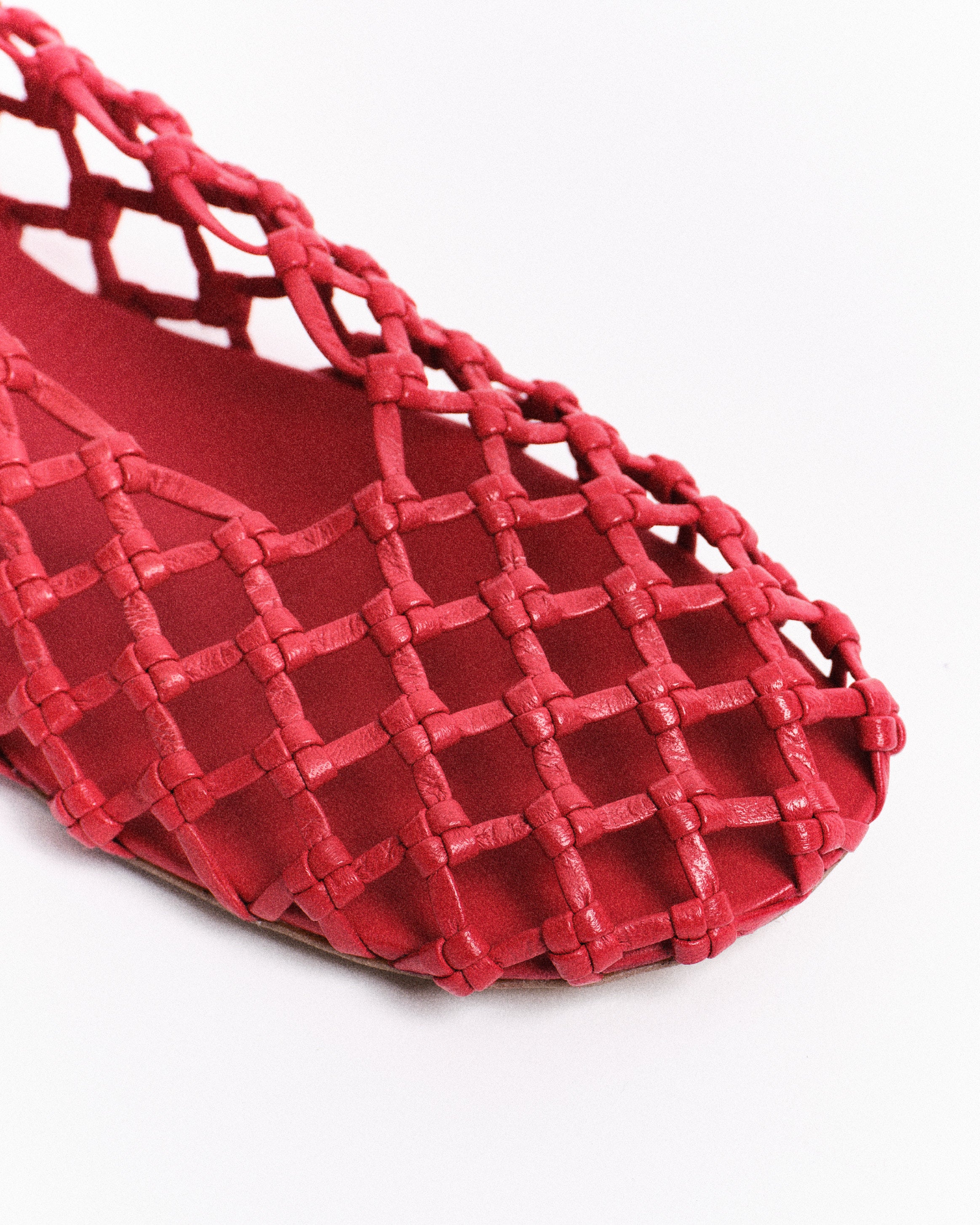 Red woven barefoot shoe details on a white background